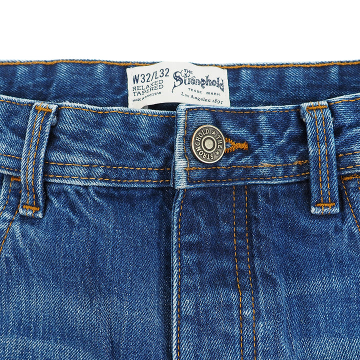 Close-up of blue denim jeans with a button and label on a white background