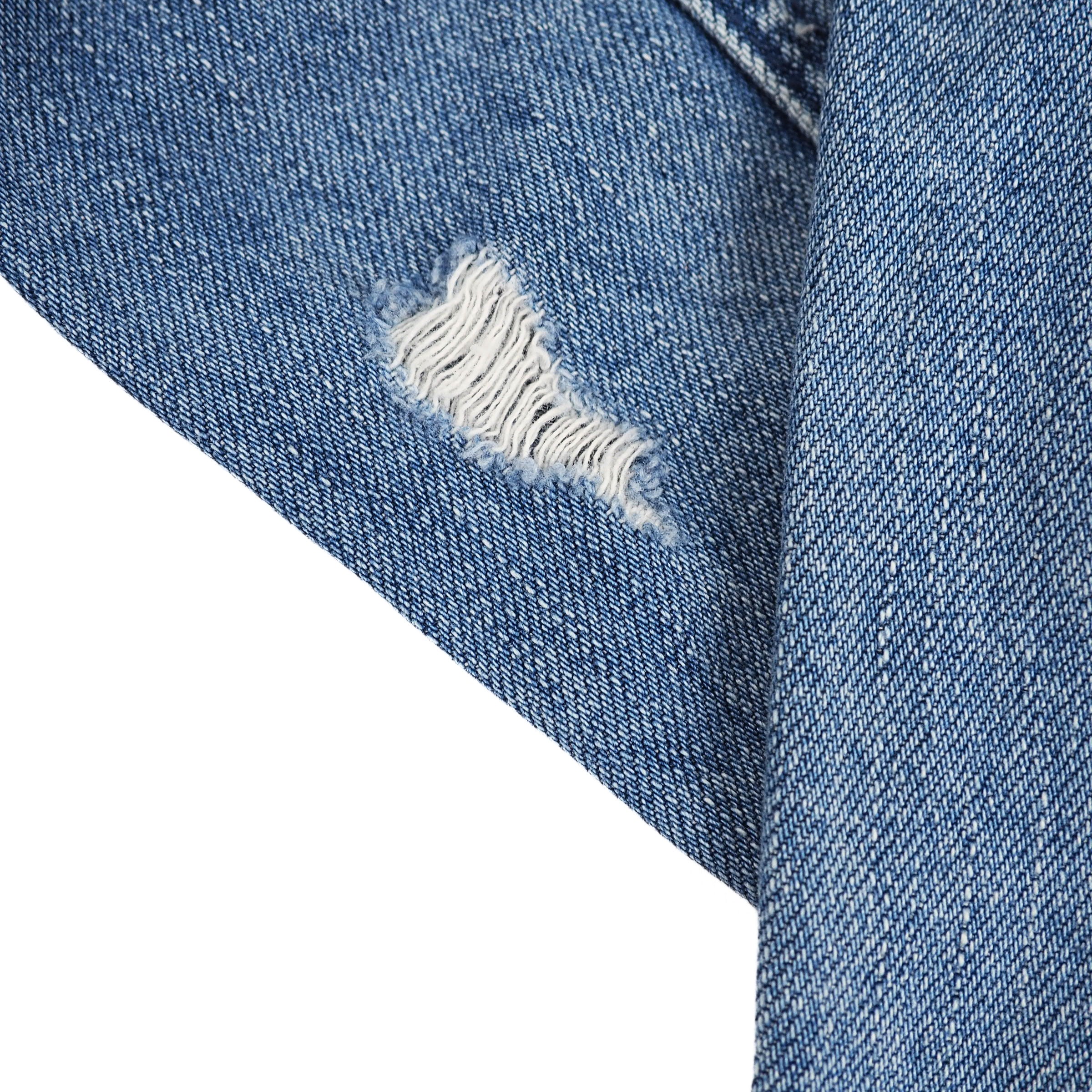 Close-up of folded blue denim fabric with a distressed area on a white background
