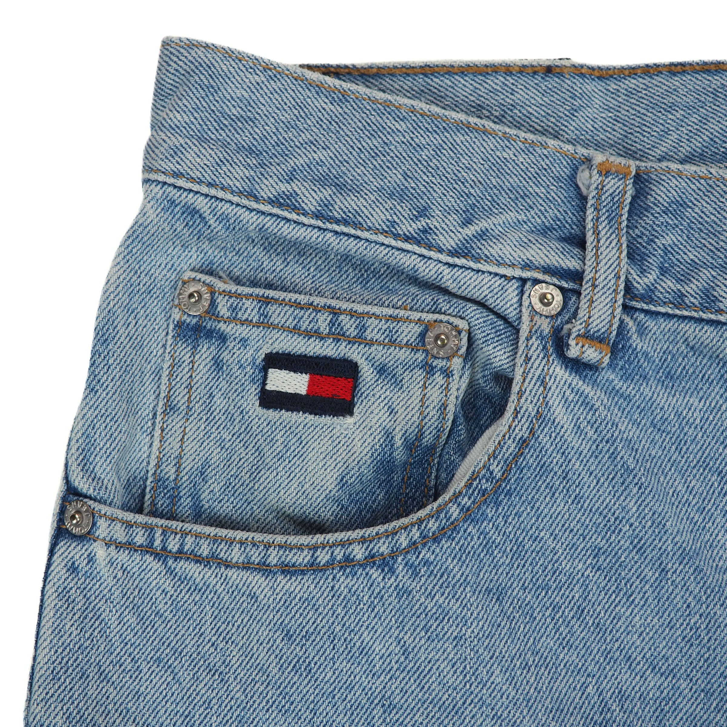 Close-up of blue jeans with a brand logo on the coin pocket against a white background