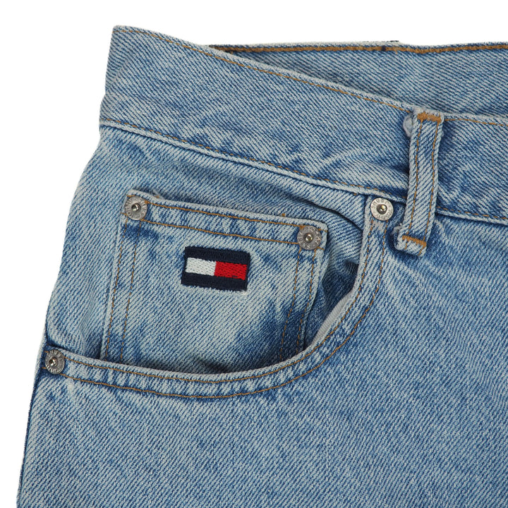 Close-up of blue jeans with a brand logo on the coin pocket against a white background