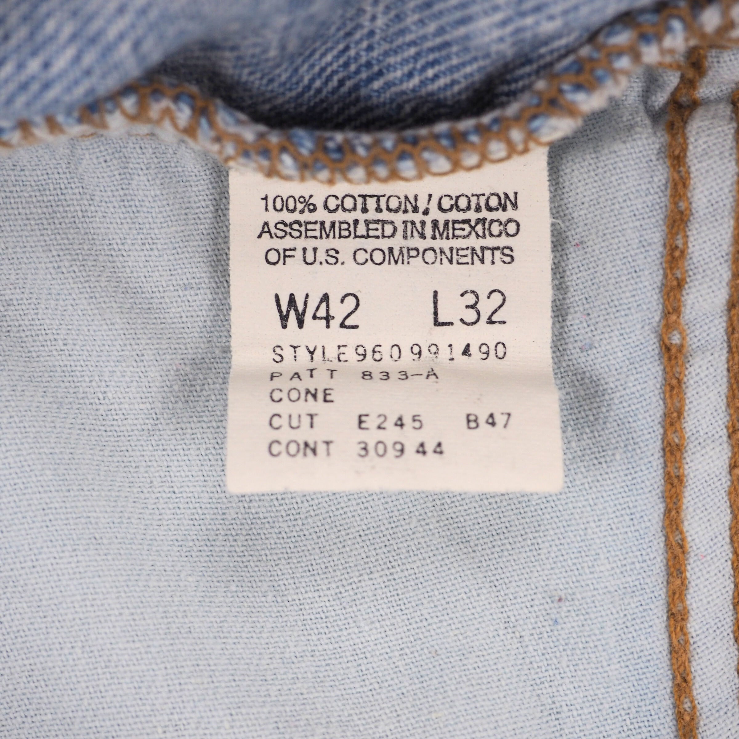 White clothing care label on denim fabric with black text and numbers