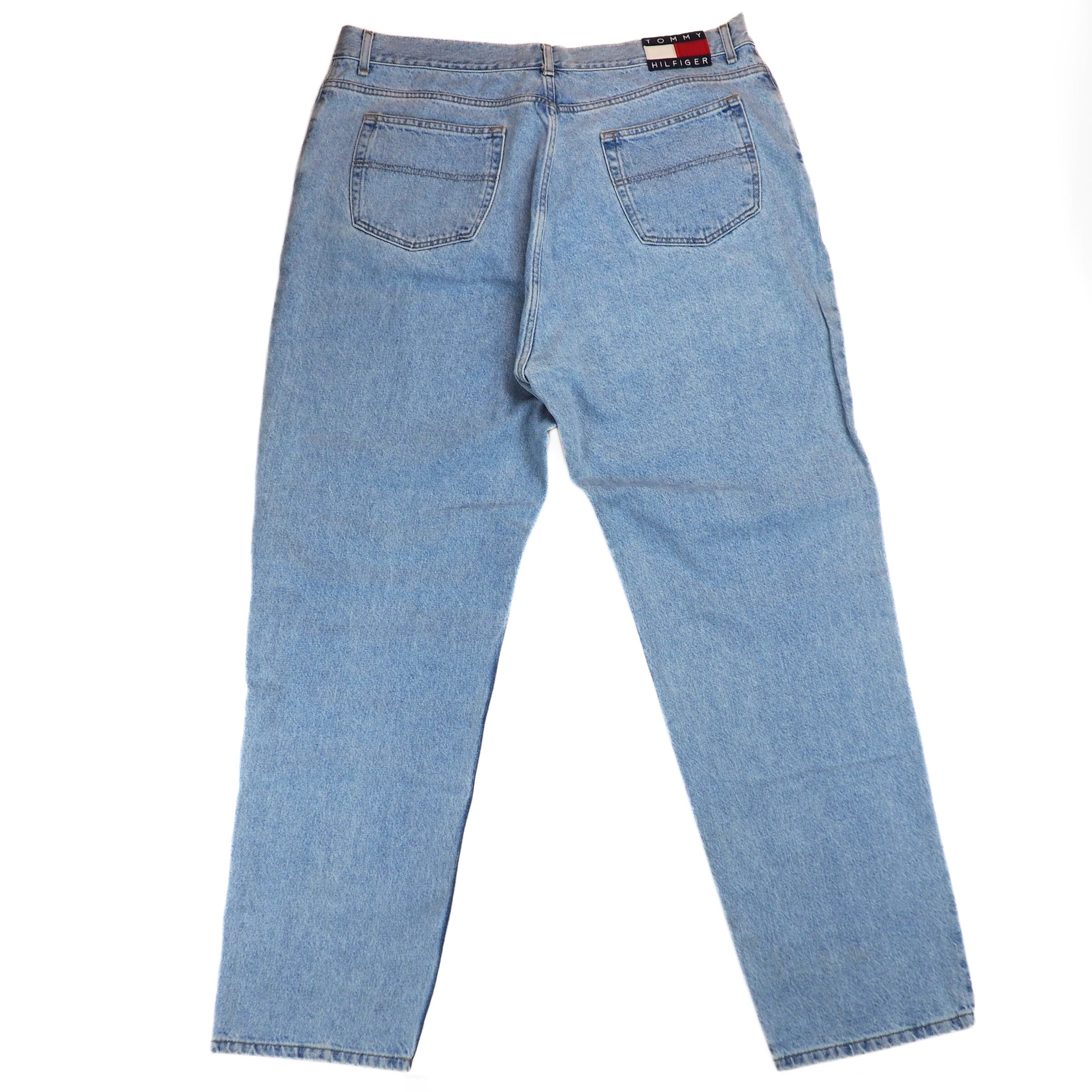 Back view of a pair of light blue denim jeans on a white background