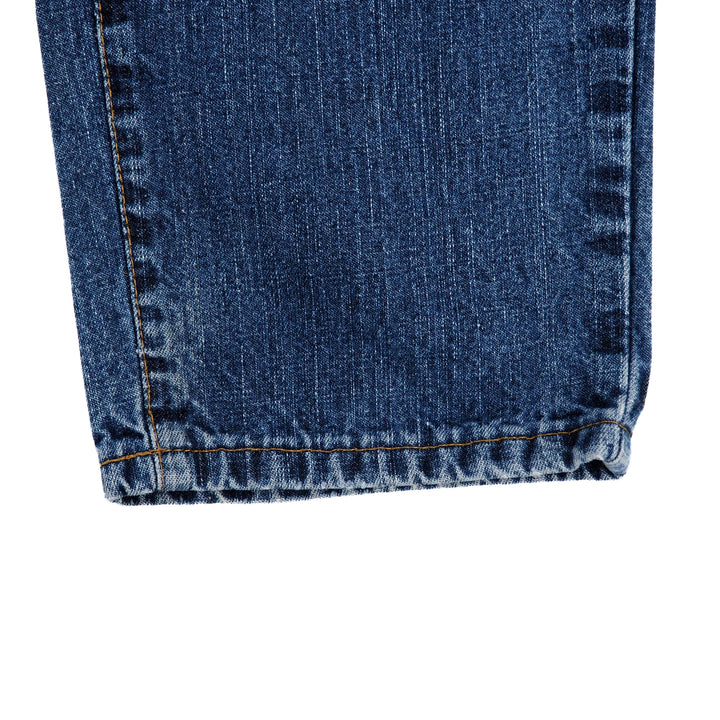Close-up of blue denim jean pant leg cuff on a white background