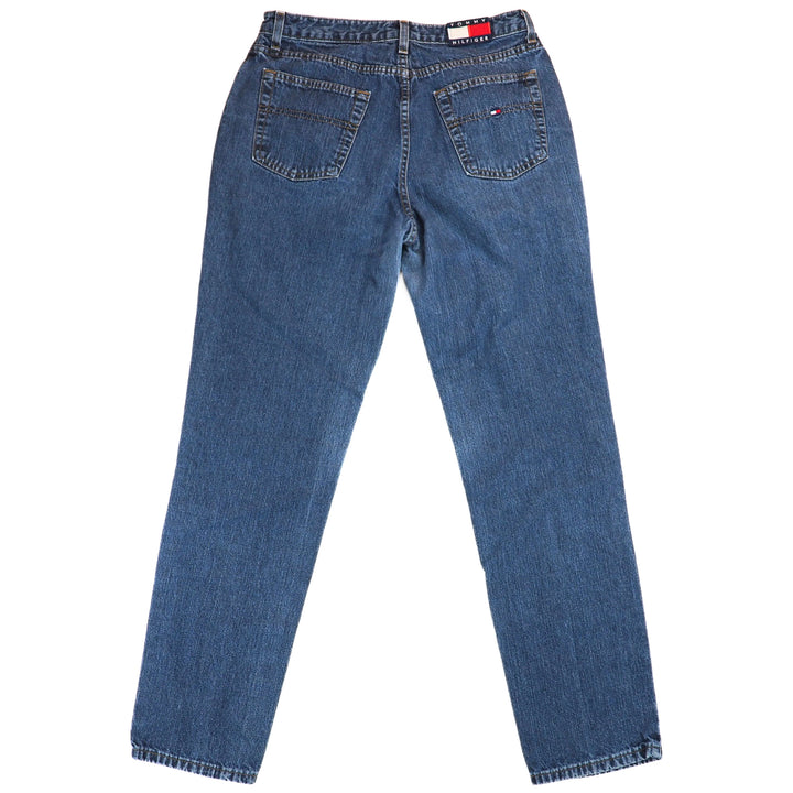 Back view of a pair of blue jeans with a Tommy Hilfiger brand logo on a white background