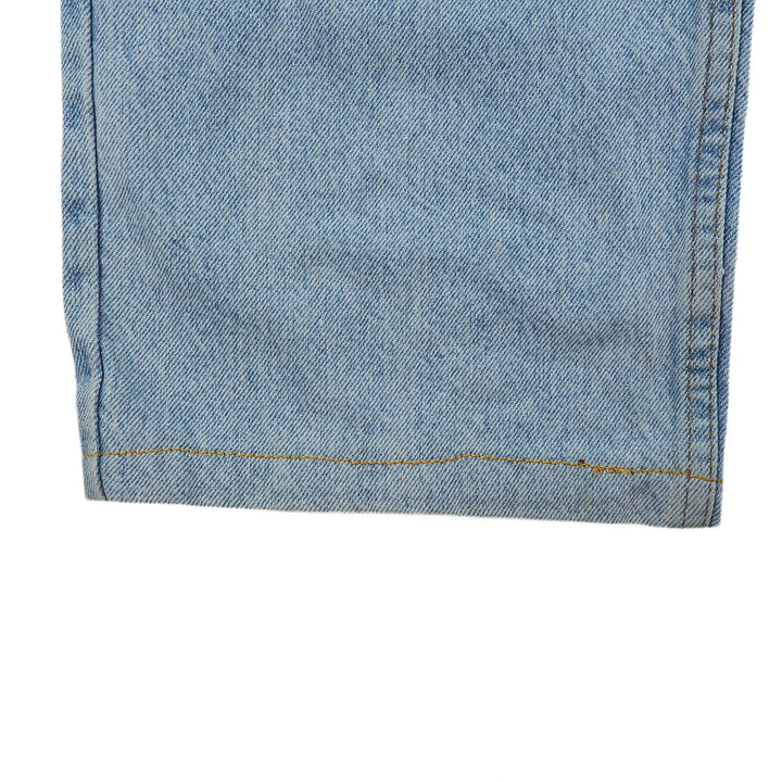 Close-up of blue denim jean pant leg with a visible seam on a white background