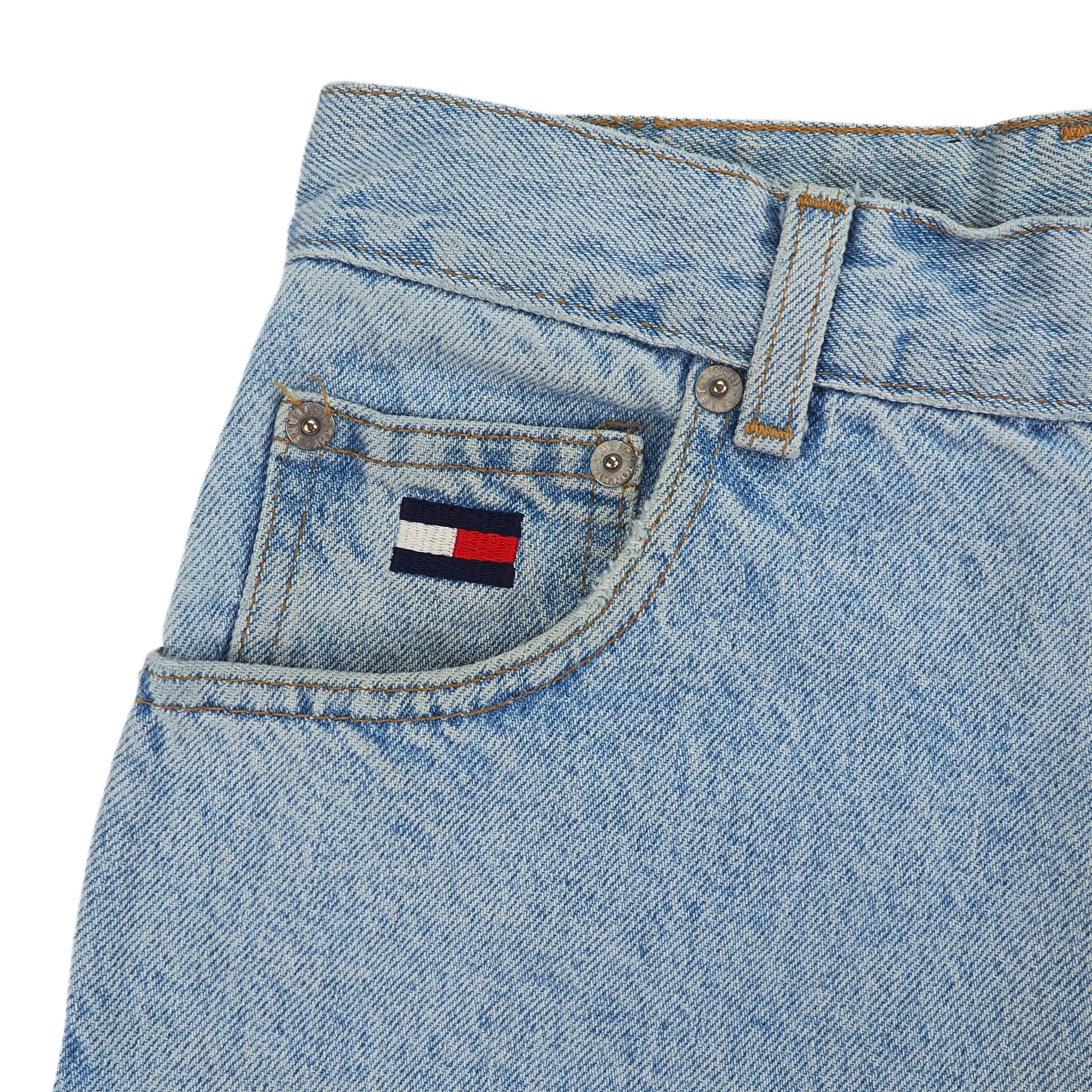 Close-up of a blue denim jean coin pocket with a Tommy Hilfiger flag logo on a white background