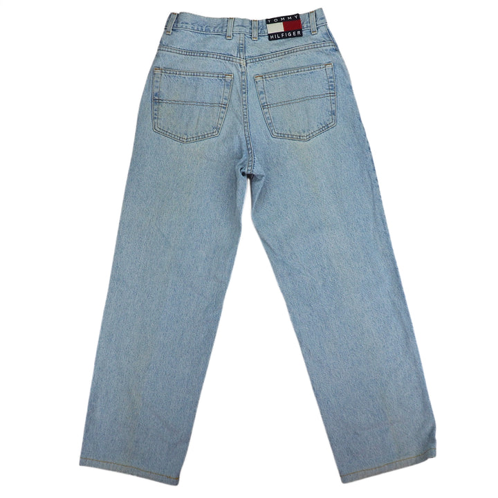 Rear view of a pair of light blue denim jeans with Tommy Hilfiger flag label on a white background