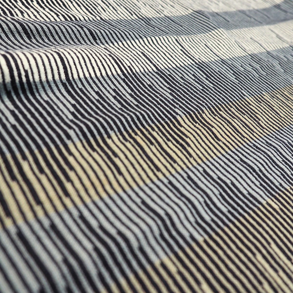 A close-up of a textured woven fabric with a striped pattern in black, off-white, and beige.