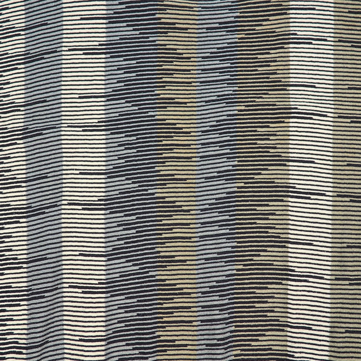 Close up detail of the geometric pattern textile in olive green, beige, black and gray.