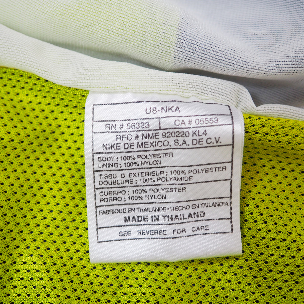 Close-up of a Nike label on a green and white garment with text details.
