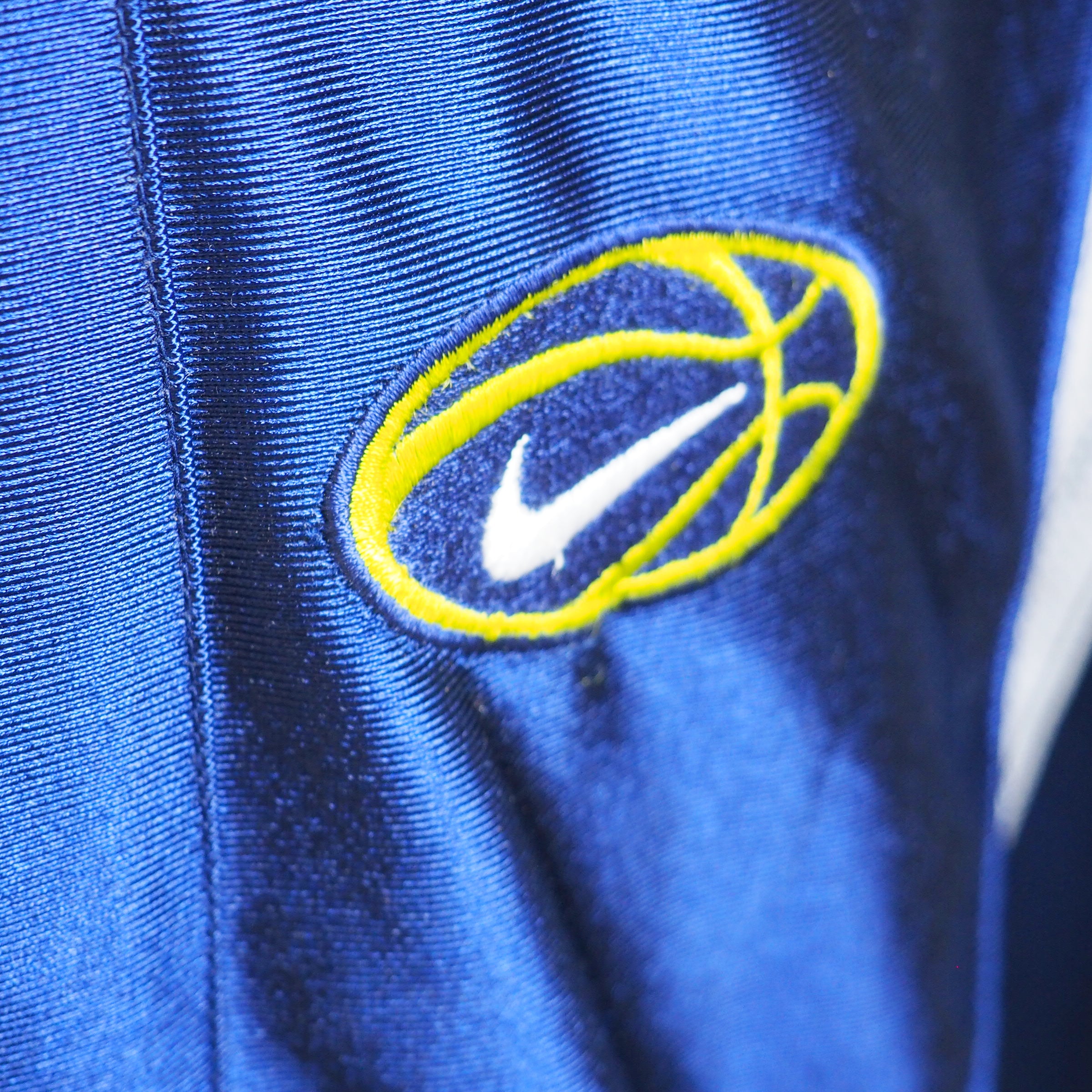 Close-up of an embroidered Nike basketball patch on a royal blue satin shell jacket, Y2K era
