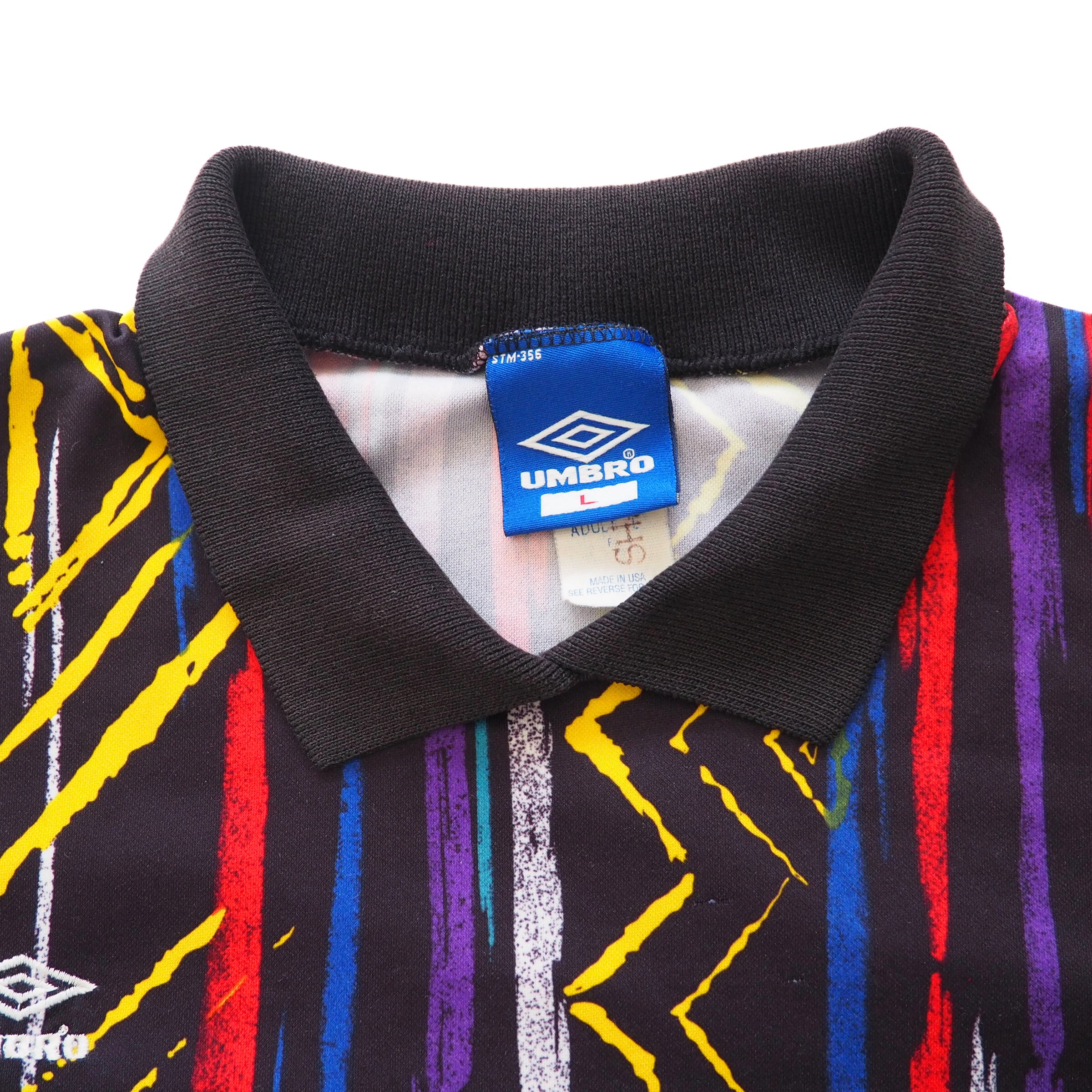 Front view of collar details of a colorful patterned keepers jersey with a visible 'Umbro' tag inside the neck on a white background