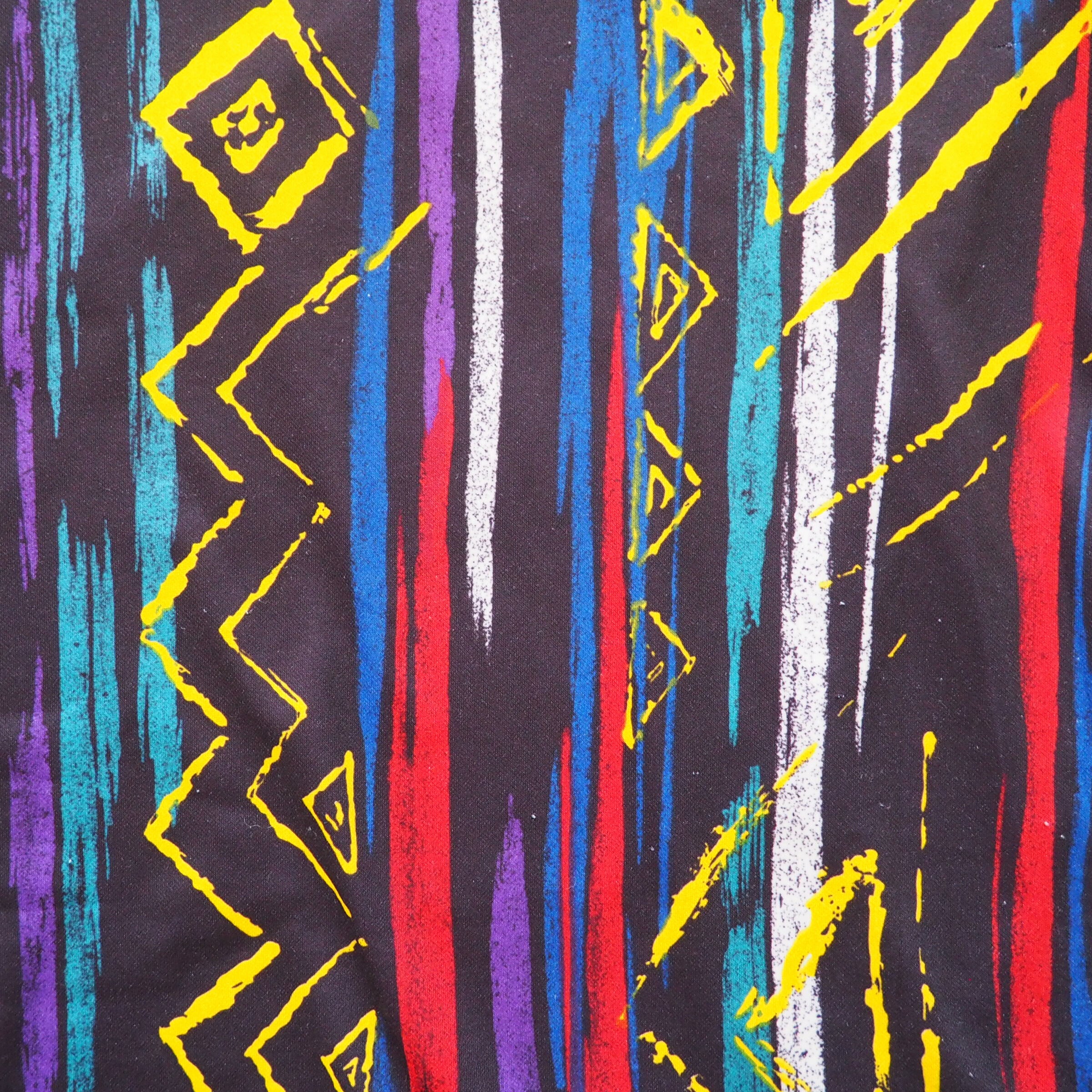 Close-up detail of a colorful abstract pattern with geometric shapes on a black background featured on a vintage umbro soccer jersey