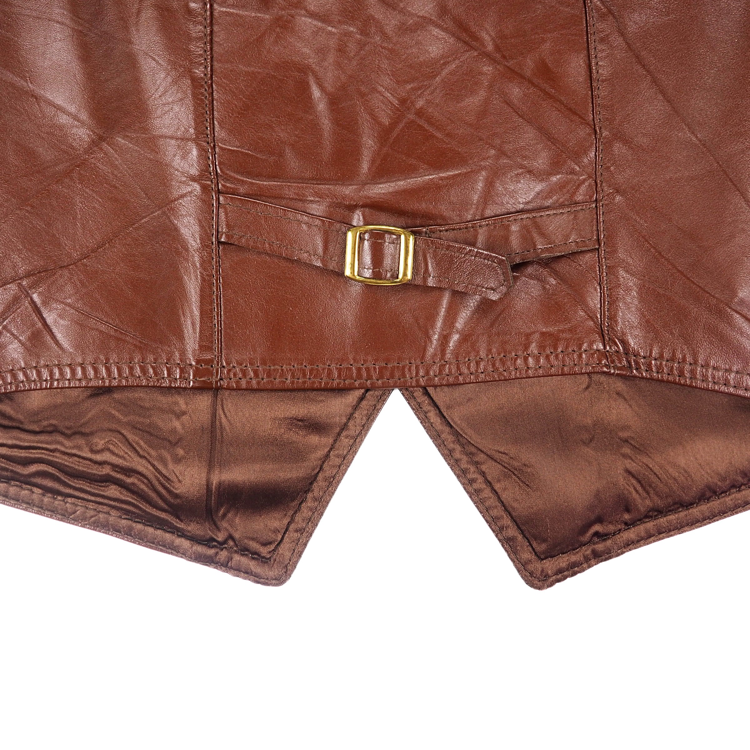 Close up of the back hem, buckle, strap and stitching of a brow leather garment.