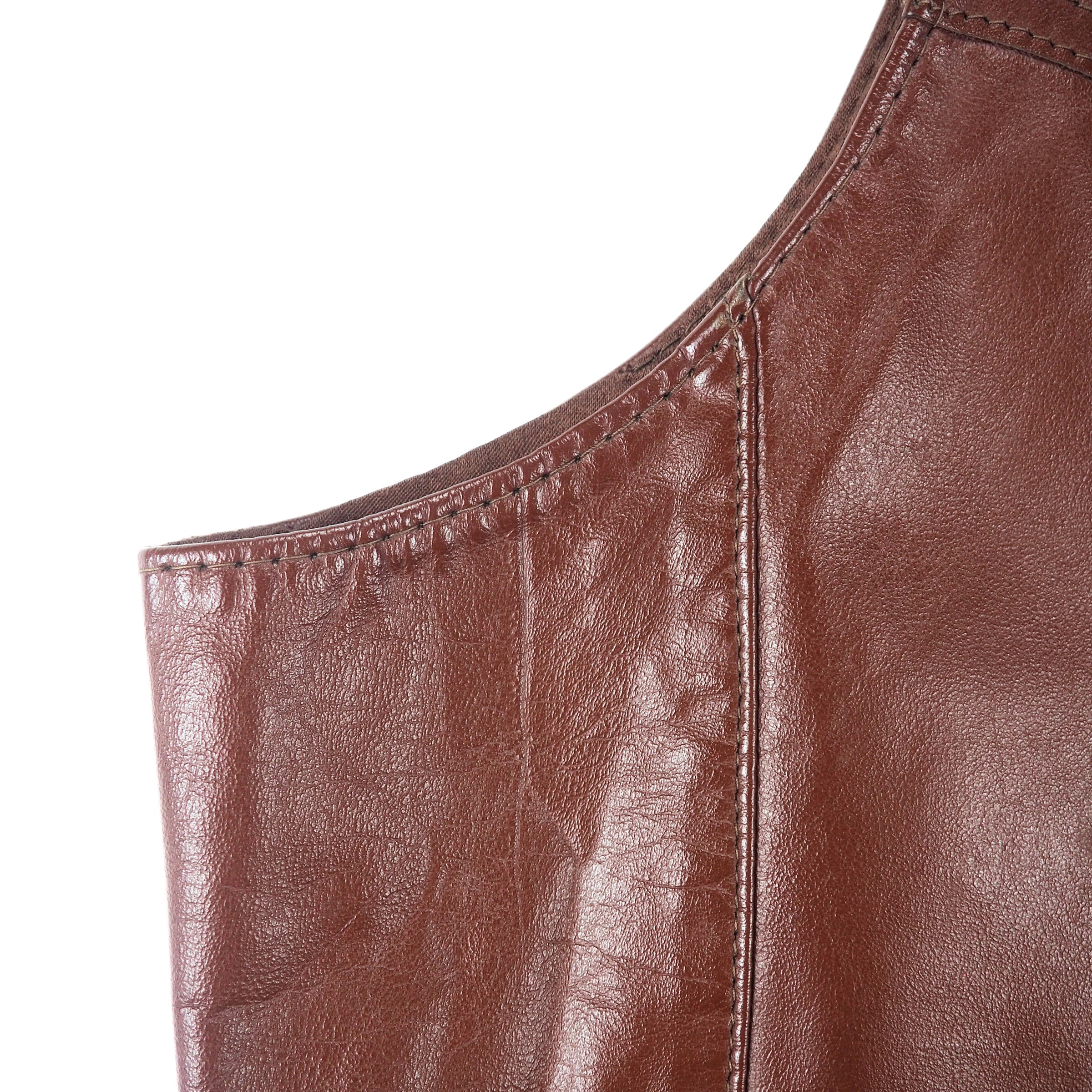 Close up of the stitching of a brown leather vest.