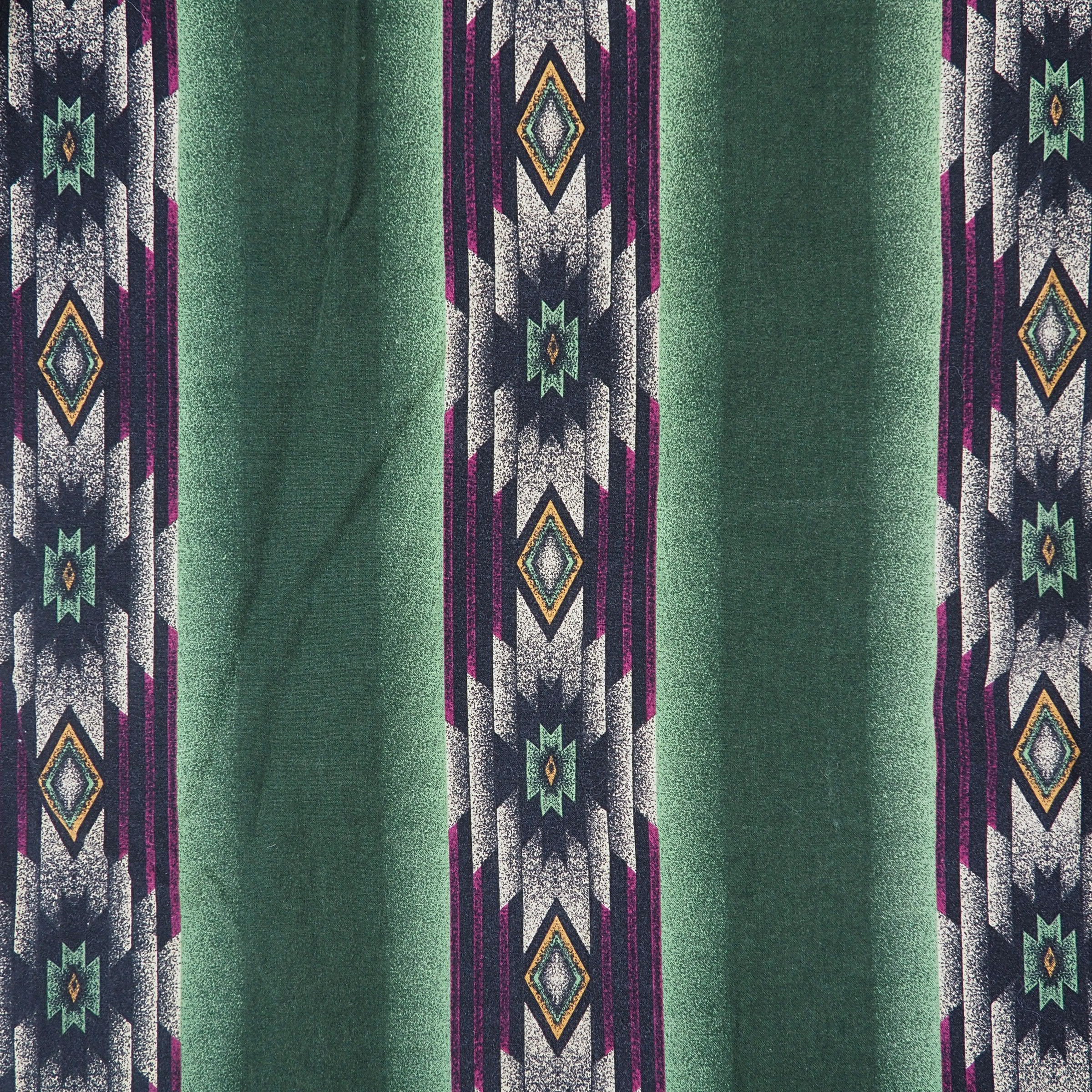 Detail of a geometric style print on fabric with colors of green, purple, orange and cream.