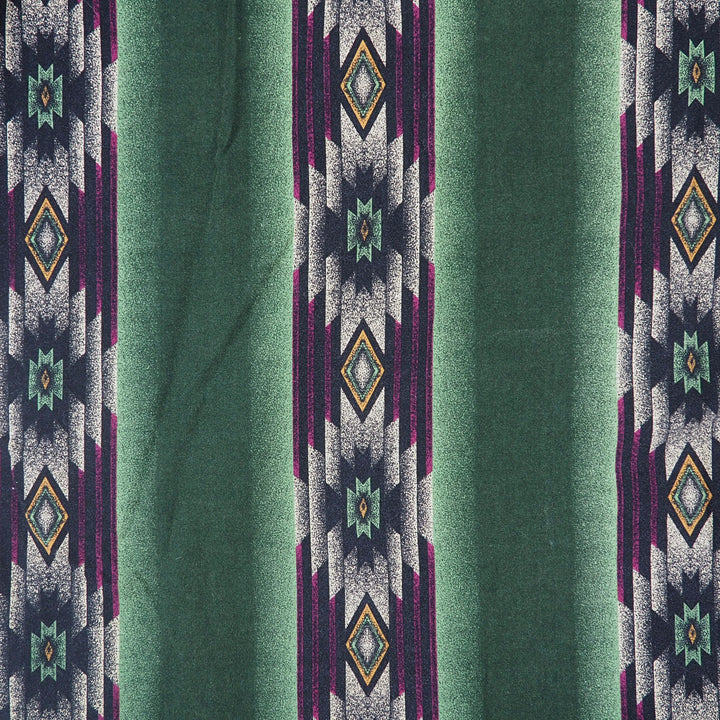 Detail of a geometric style print on fabric with colors of green, purple, orange and cream.