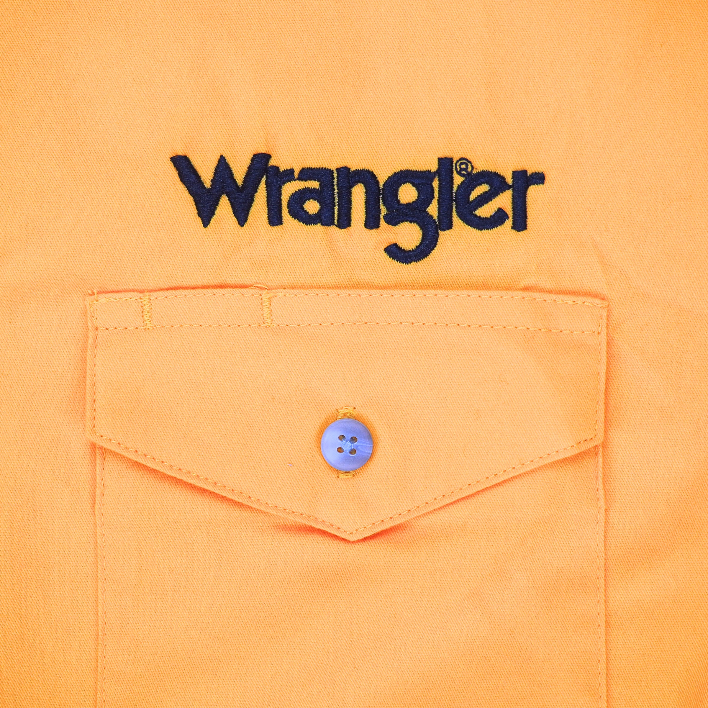Close up of a dress shirt pocket with 'Wrangler' embroidery