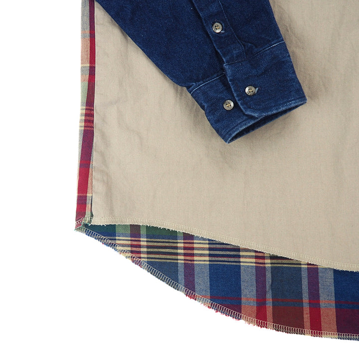 Close up of a denim sleeve cuff laying on the body of a khaki colored shirt with plaid trim.