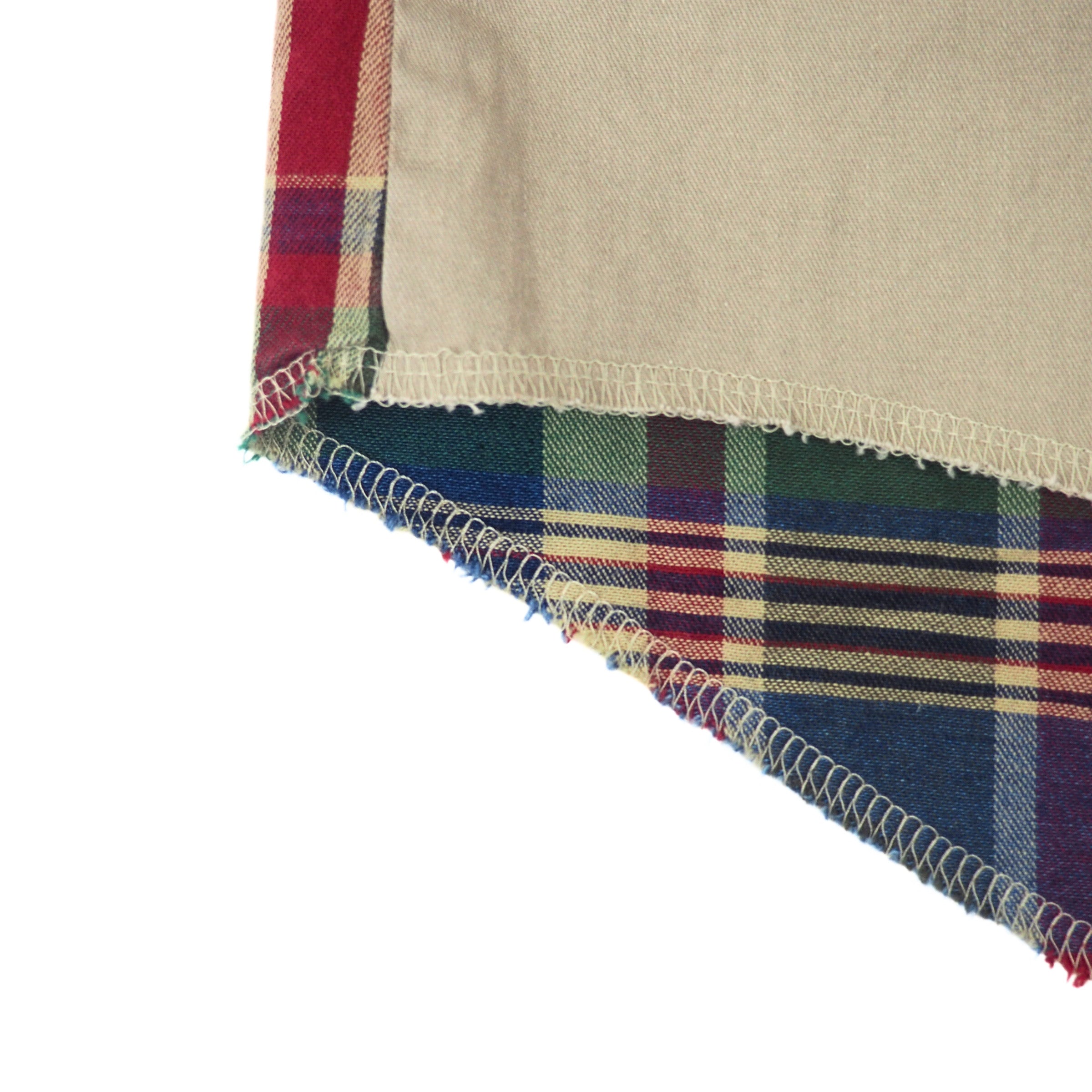 Close up of the hem and stitching details of a shirt with khaki and plaid colours.