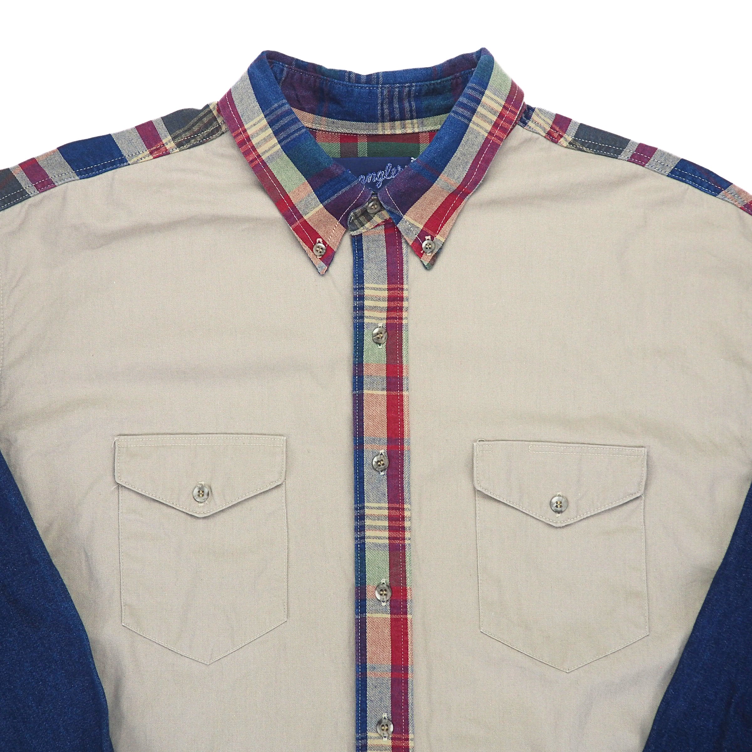 Close up of the breast pockets and collar of a cream colored shirt with plaid and denim trim.