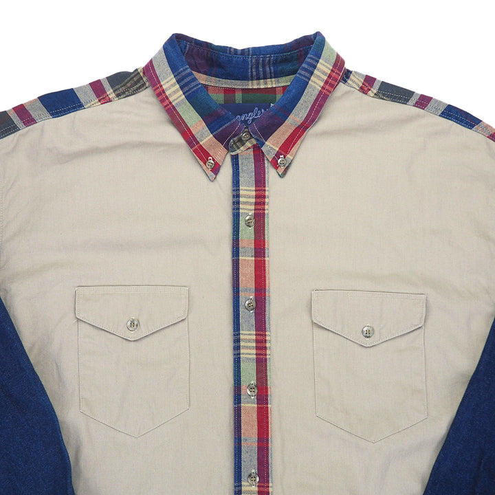 Close up of the breast pockets and collar of a cream colored shirt with plaid and denim trim.
