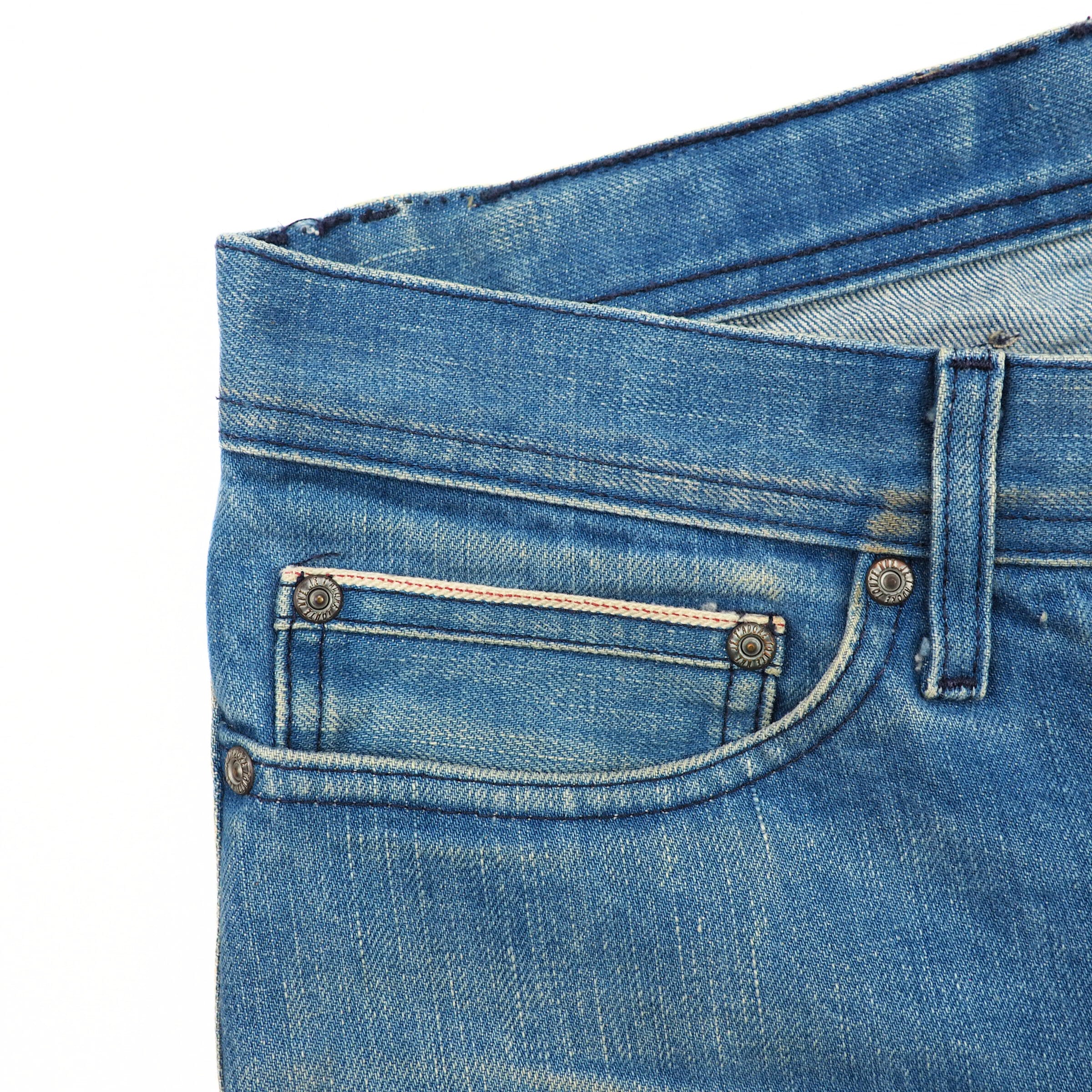 Close-up of blue jeans with a focus on the coin pocket area.