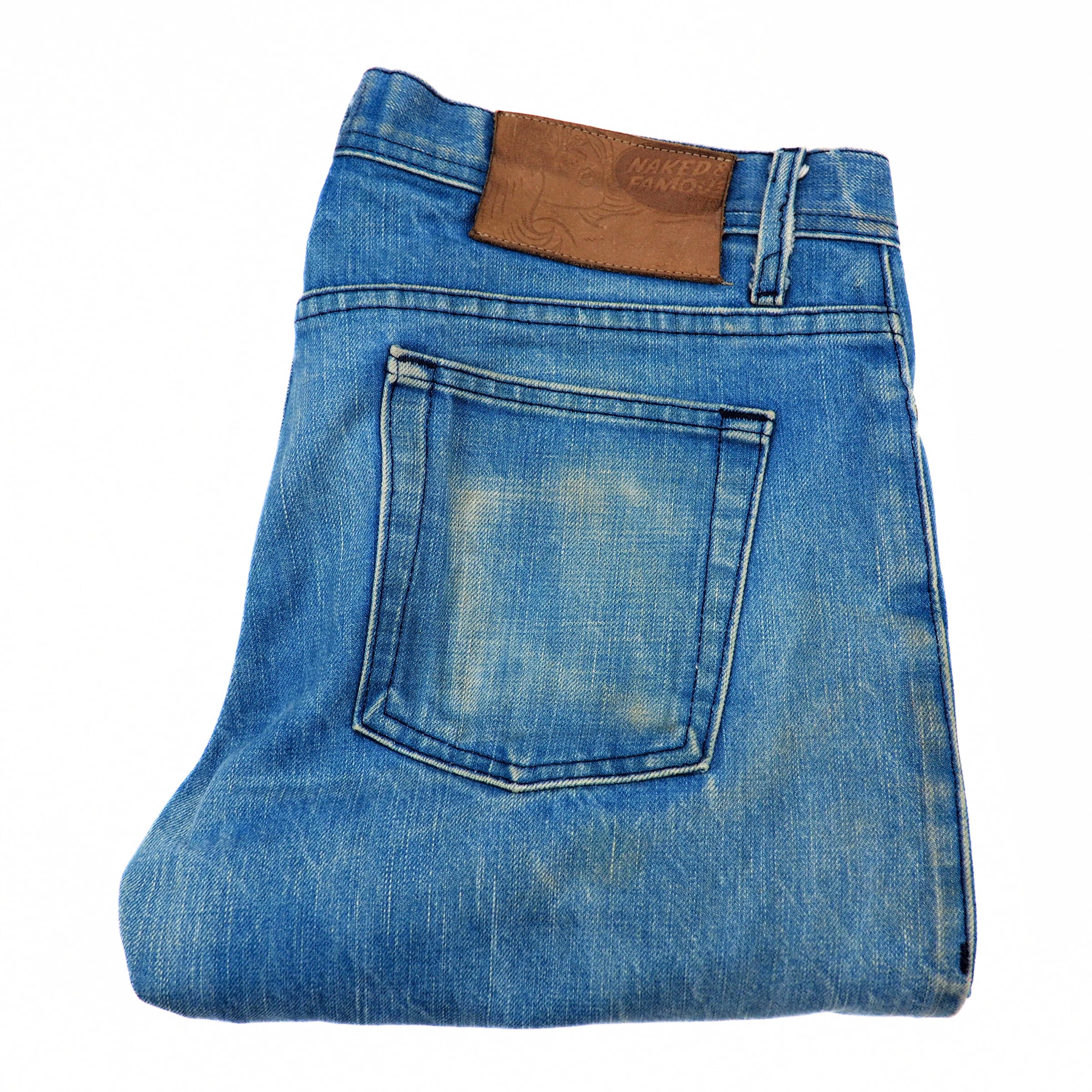 Folded blue denim jeans with a brown leather patch on a white background