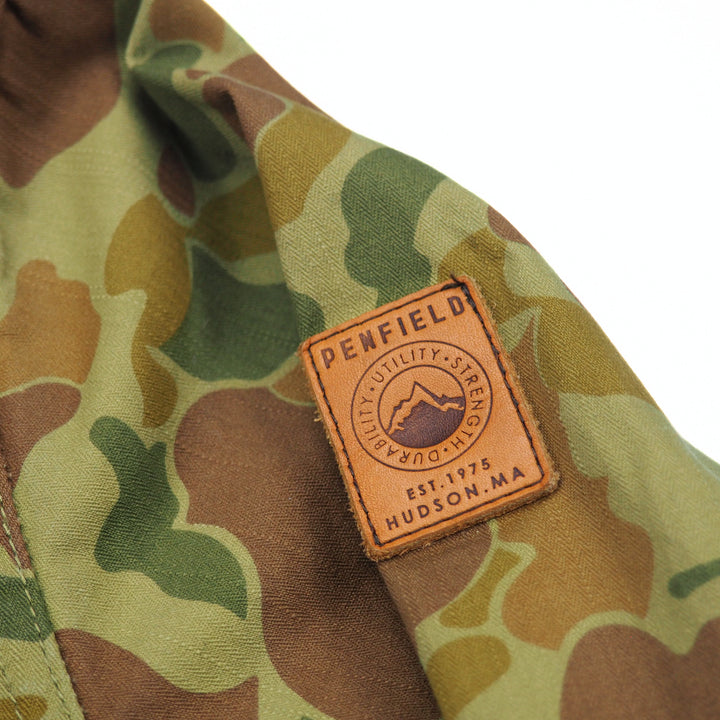 Camouflage jacket sleeve shoulder with a leather Penfield patch on a white background