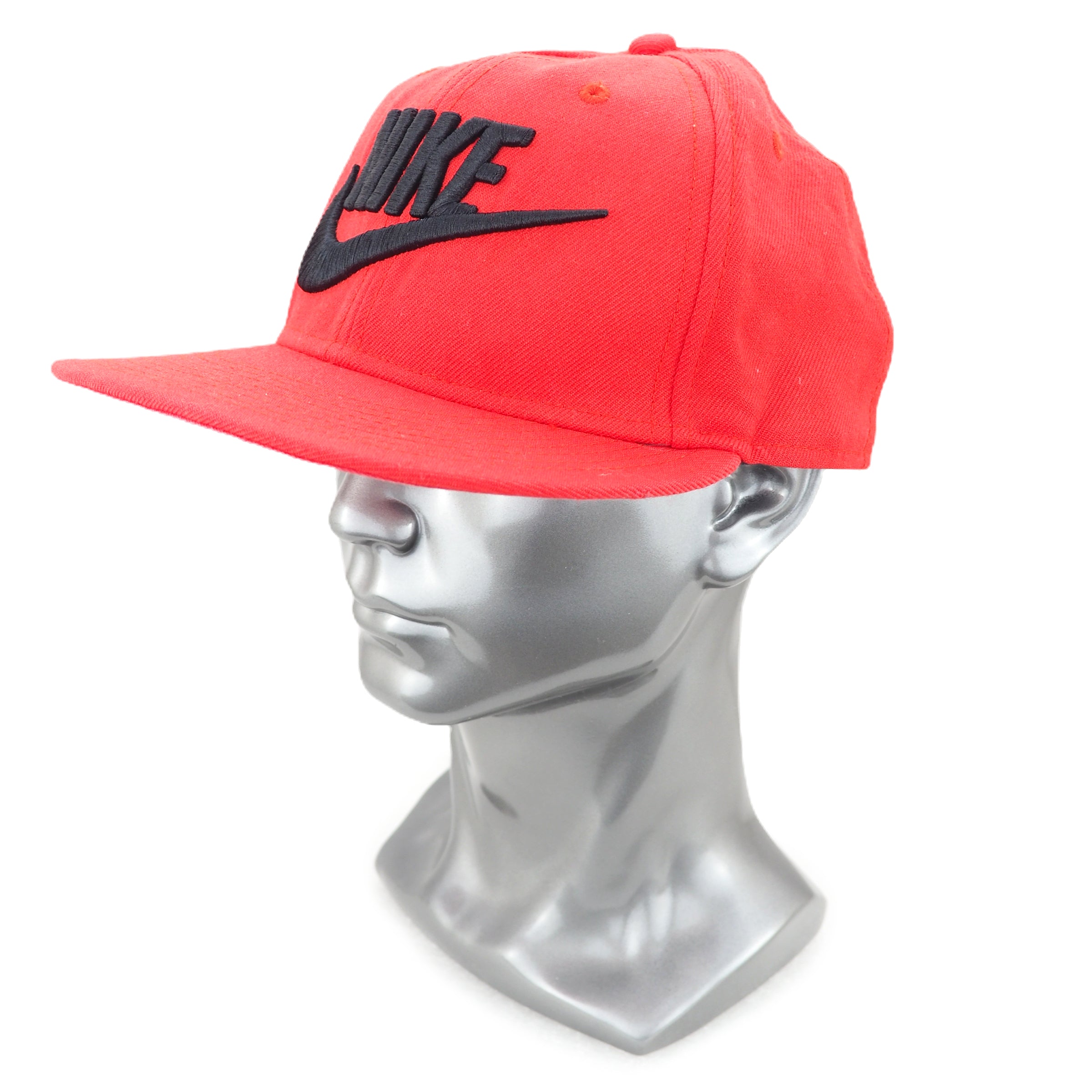 Red cap with black Nike logo on a silver mannequin head against a white background