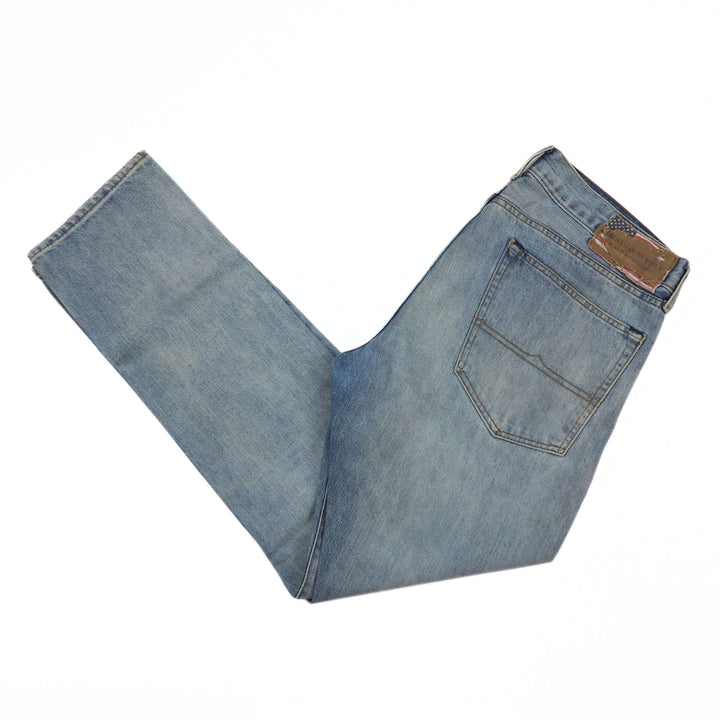Folded blue jeans with a brown patch on a white background