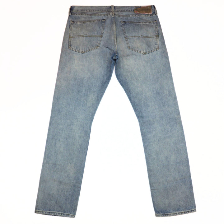 Back view of a pair of light blue denim jeans on a white background