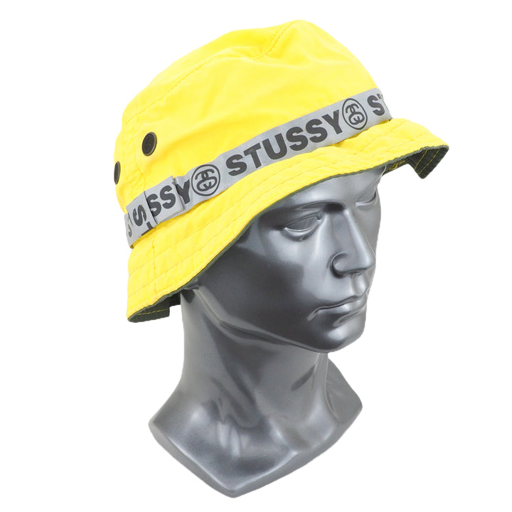 Yellow bucket hat with Stussy logo on a mannequin head against a white background