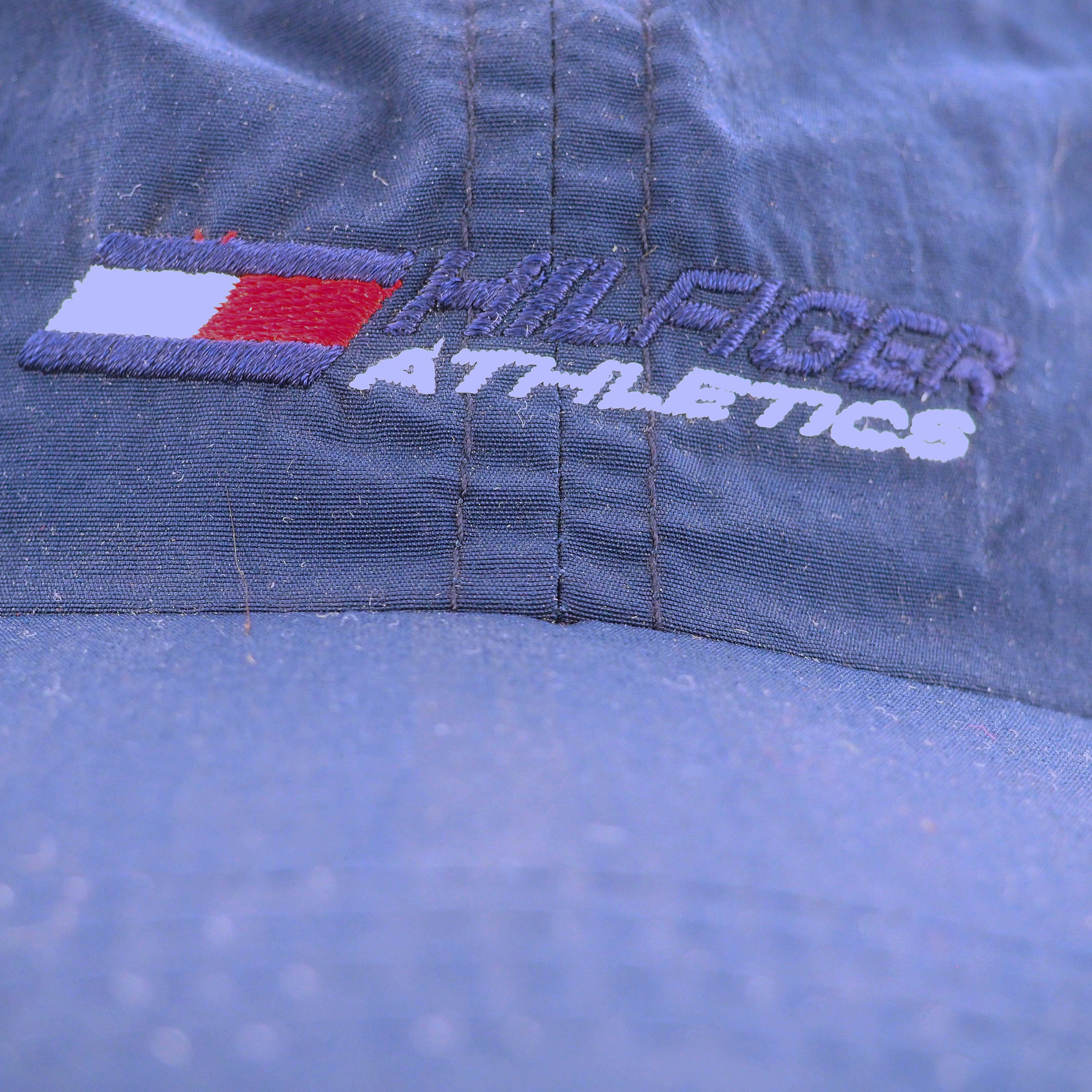 Close-up of Tommy Hilfiger Athletics logo on a blue fabric background