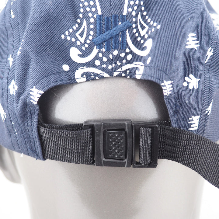 Blue cap with white patterns and black strap on a mannequin head