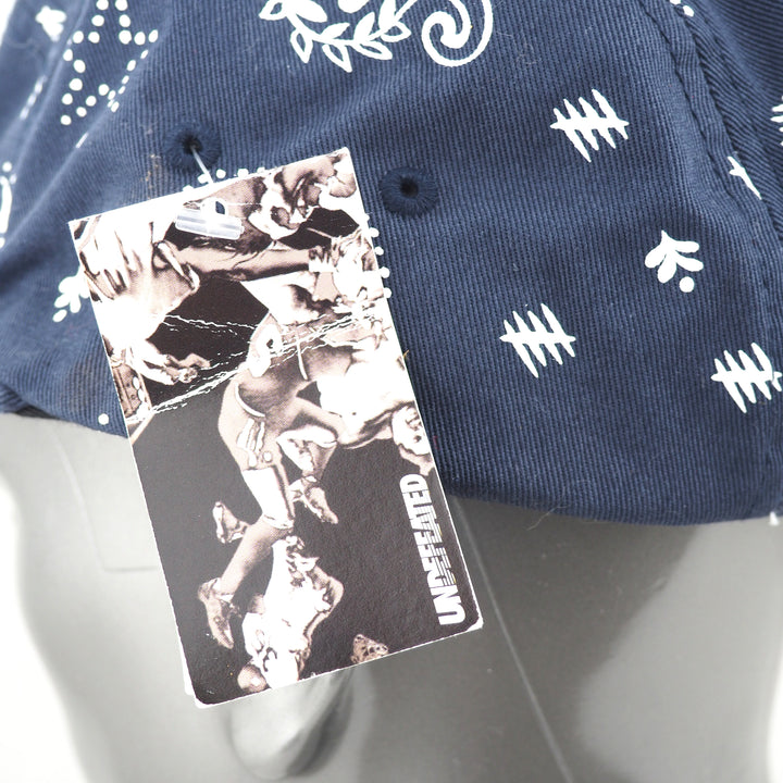 Navy blue cap with white paisley patterns and a black and white graphic tag branded UNDEFEATED