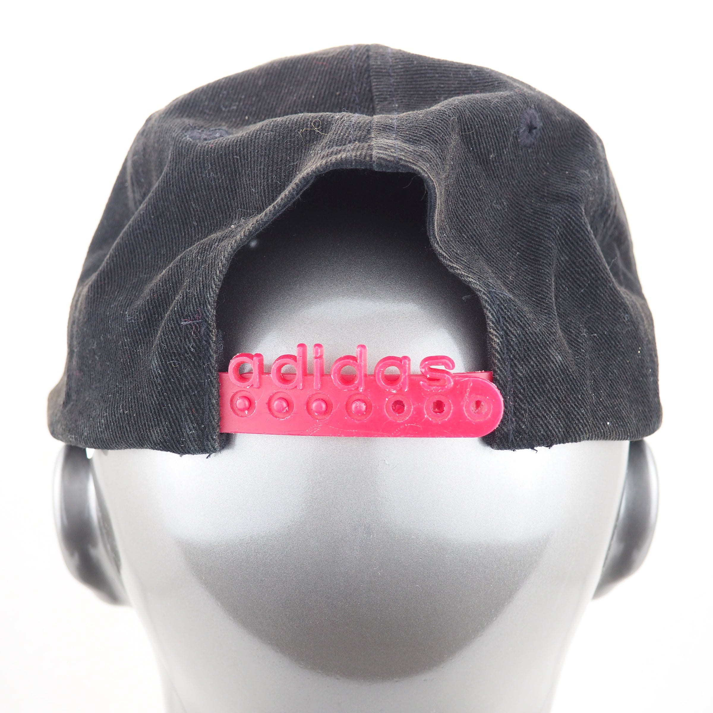 Black cap with pink Adidas logo on a mannequin head against a white background