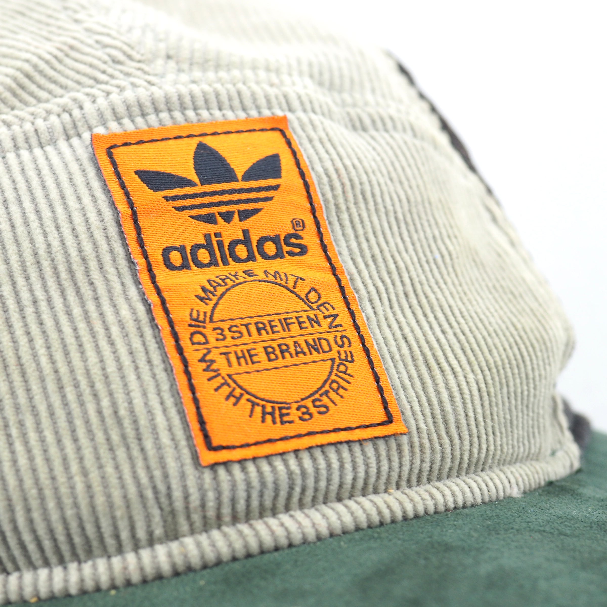 Close-up of an Adidas logo on a corduroy cap with a white background