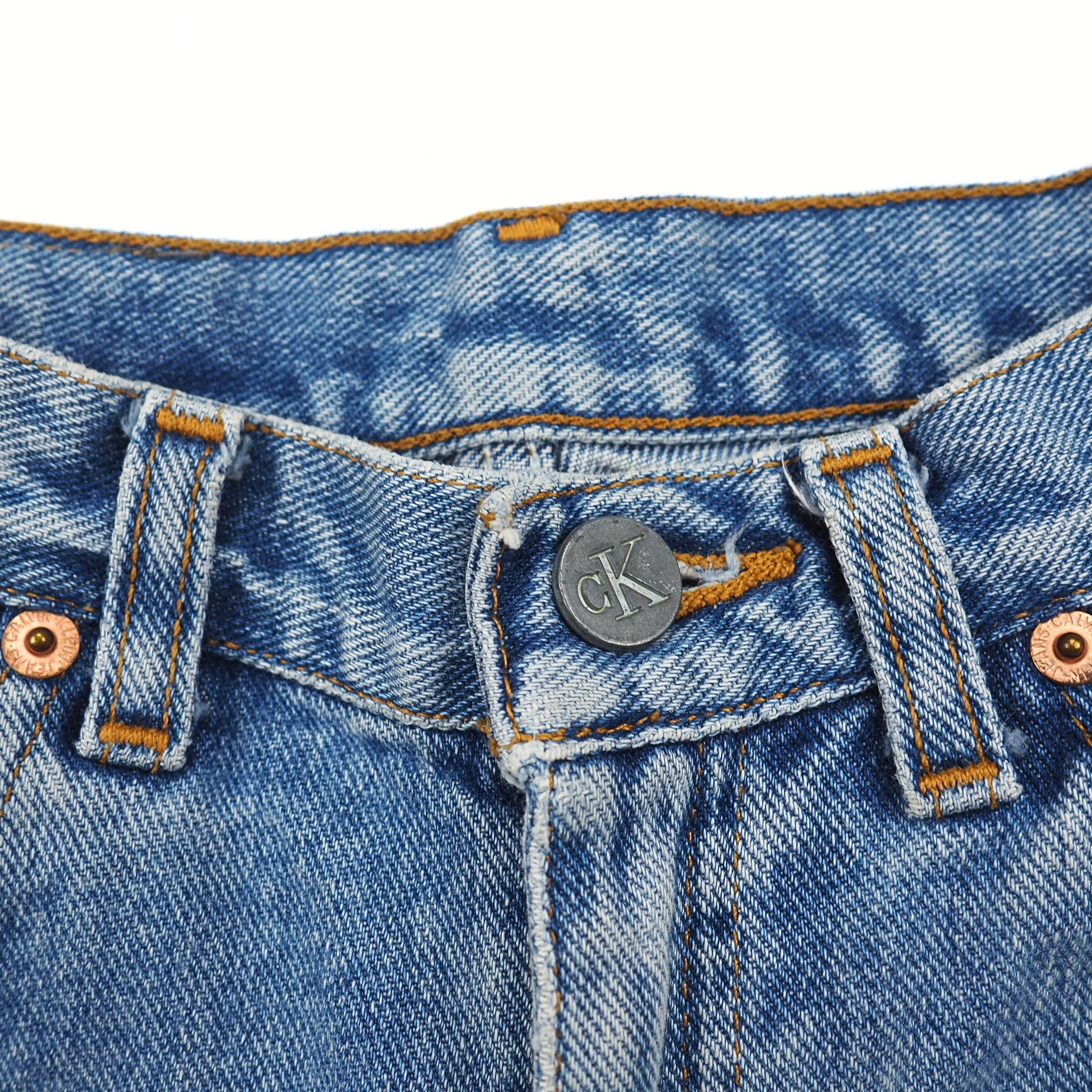 Close-up of blue denim jeans with a brand logo on the button area.
