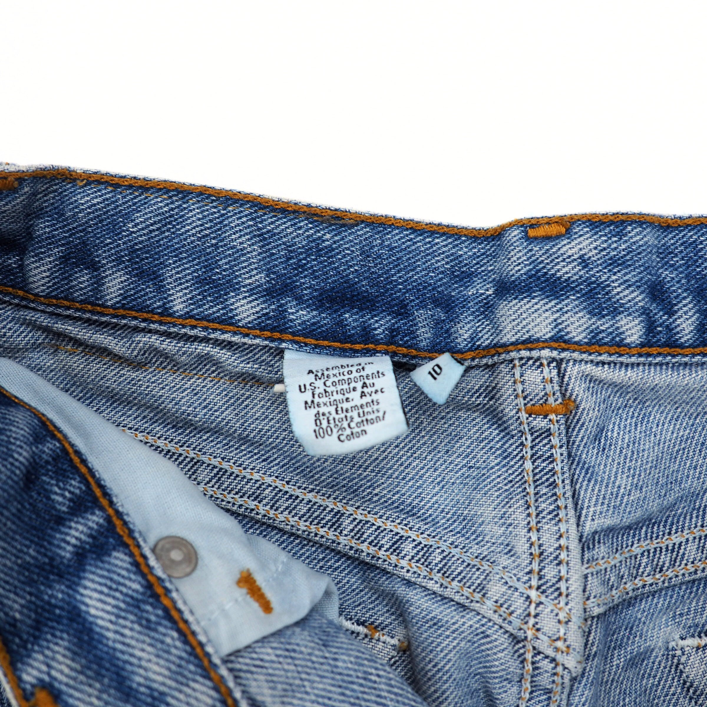 Close-up of blue denim jeans with a care label on a white background