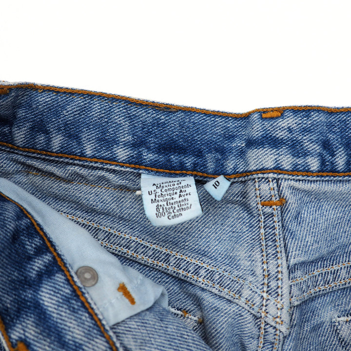 Close-up of blue denim jeans with a care label on a white background