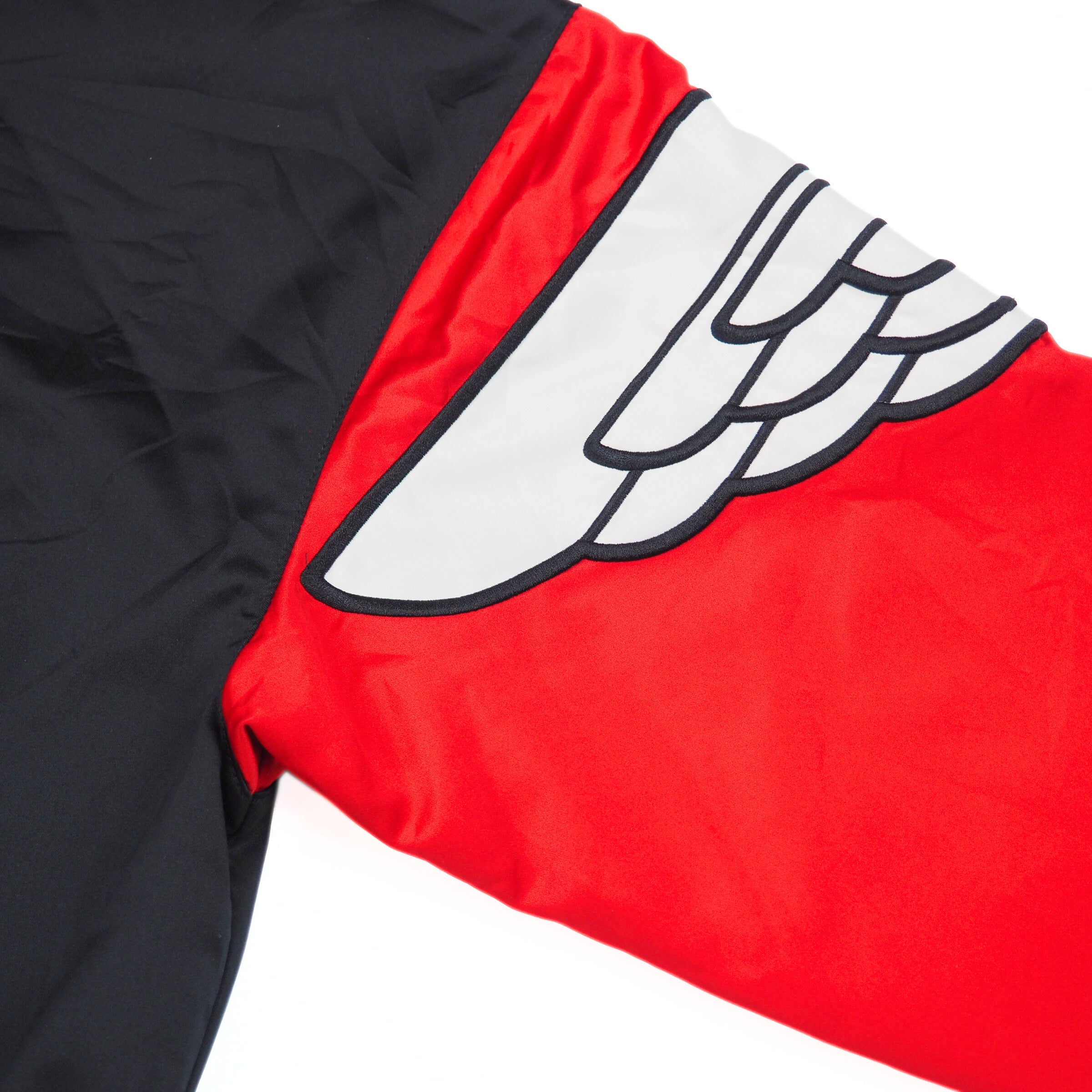 Red and black jacket sleeve with a white winged logo on a white background