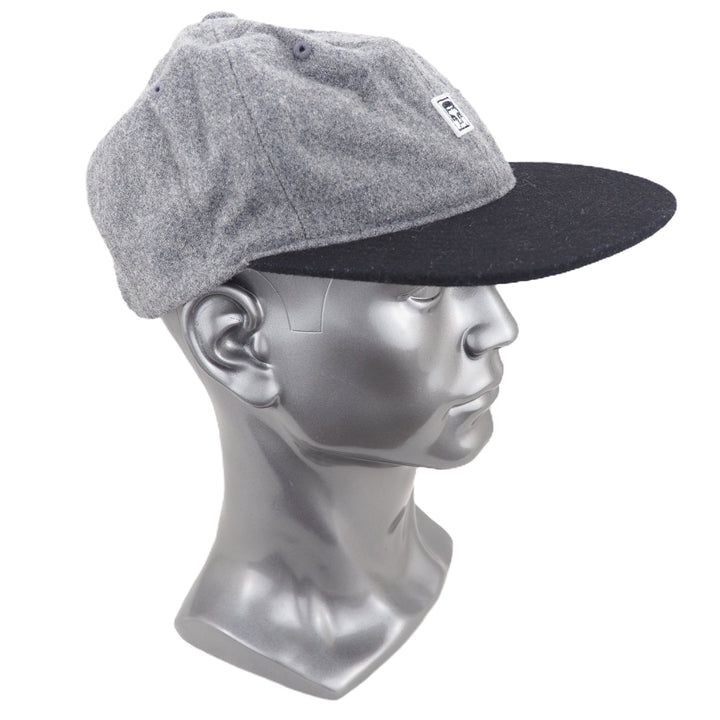Gray and black cap on a silver mannequin head against a white background