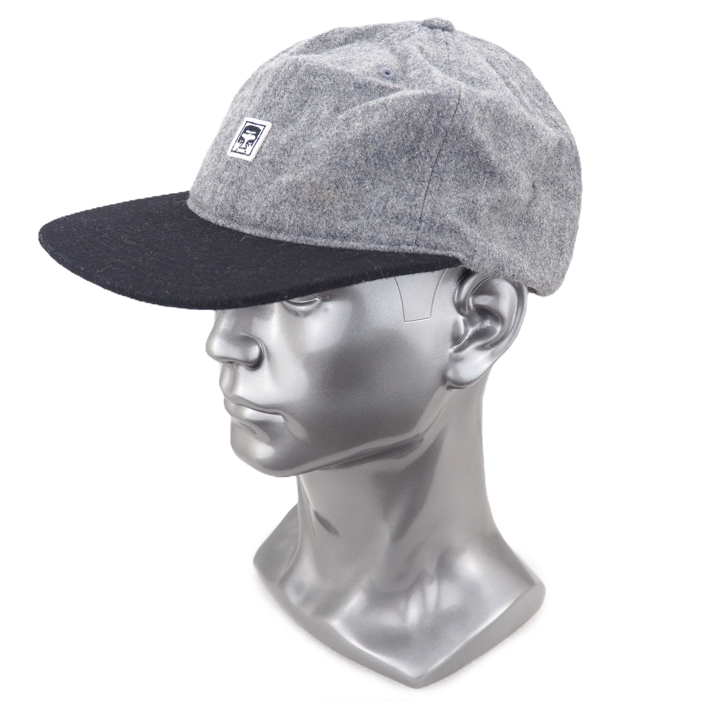 Gray and black cap on a silver mannequin head against a white background