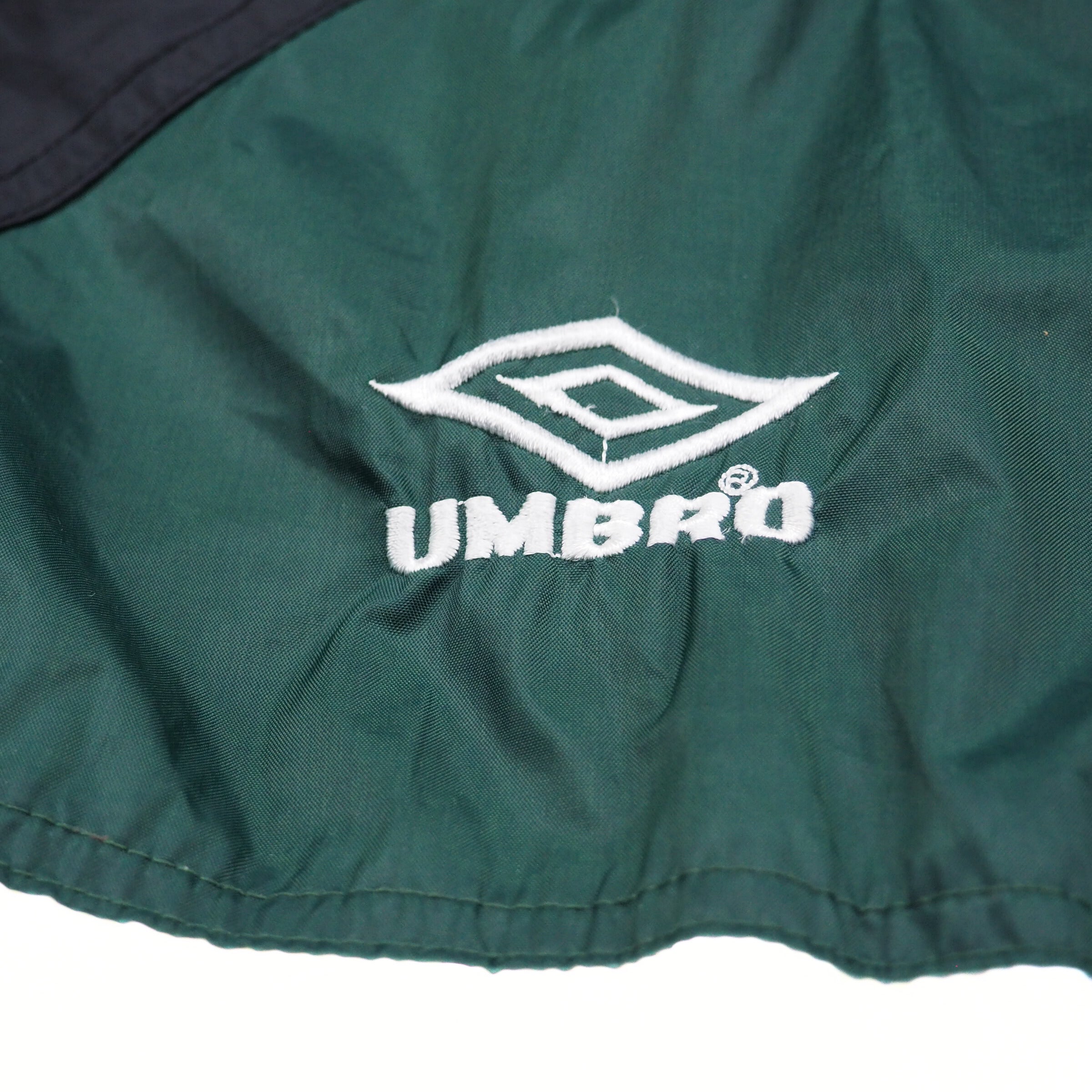 Close-up of a green jacket with an Umbro logo on a white background