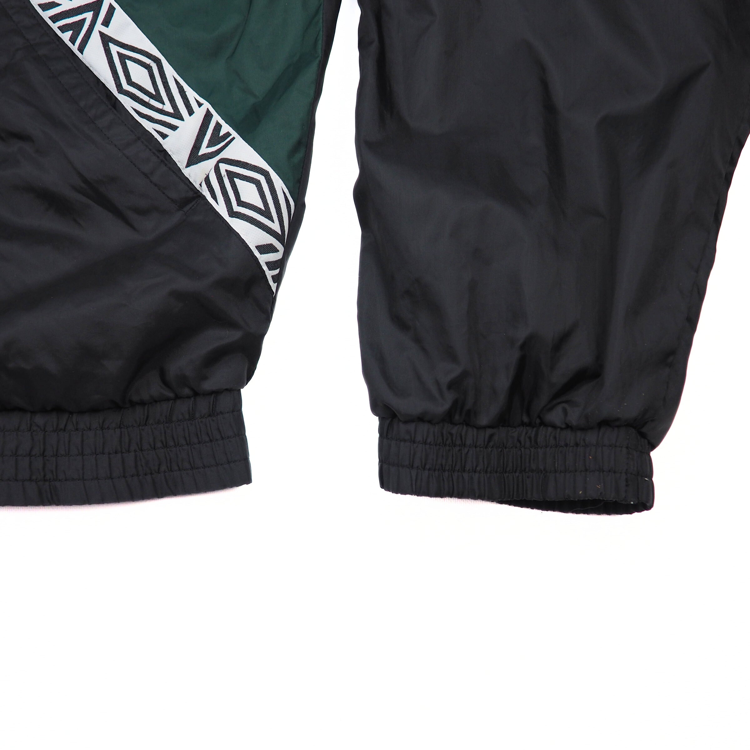 Close-up of black and green jacket sleeve and body with geometric pattern on a white background