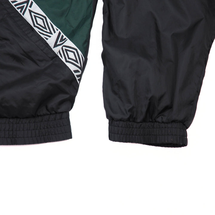 Close-up of black and green jacket sleeve and body with geometric pattern on a white background
